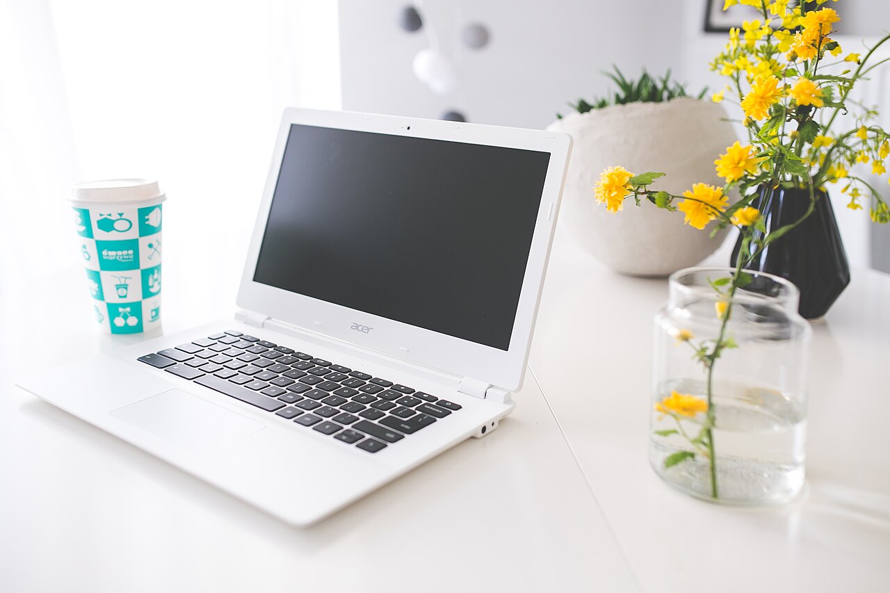 A calm desk workspace with coffee, a laptop, and a notebook