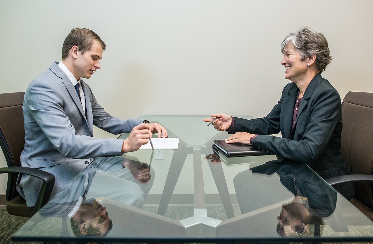 A young man in a job interview across a table from an interviewer