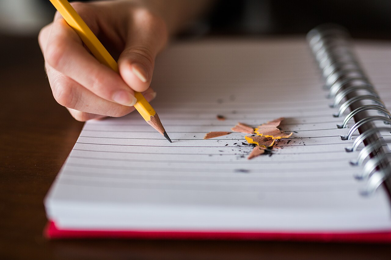 A hand writing notes with a pencil