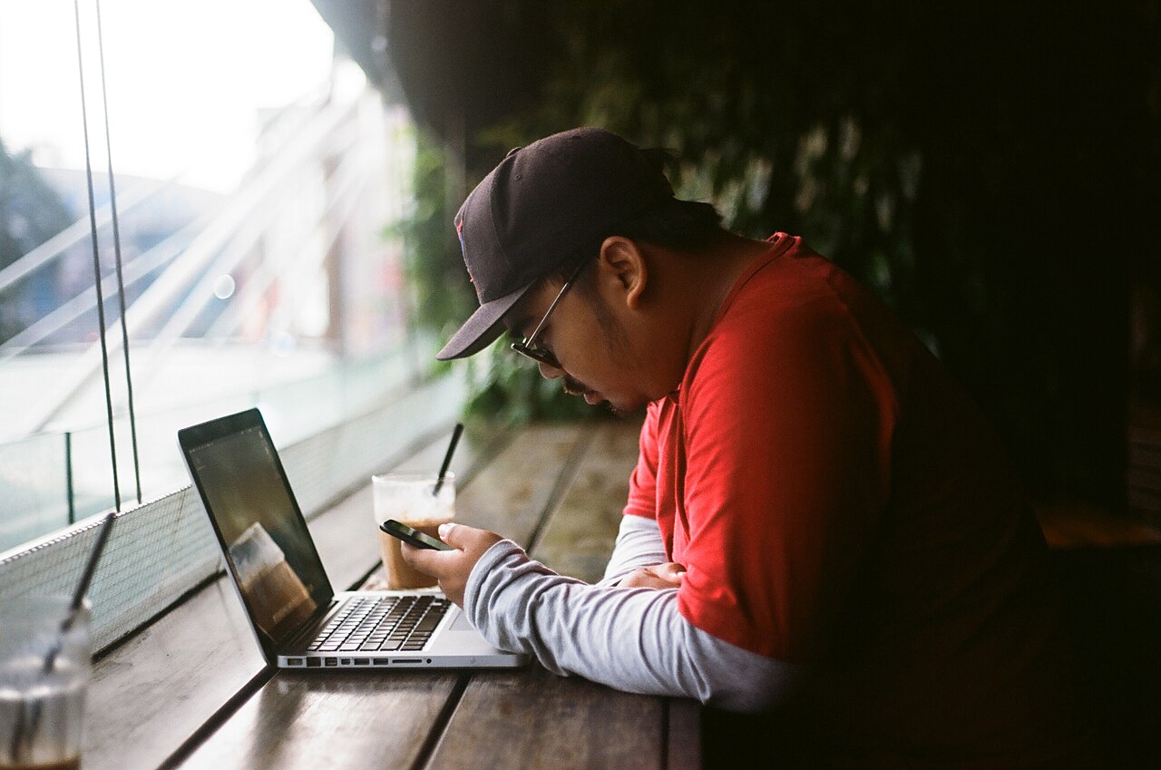A man sitting with a laptop, pausing instead of working
