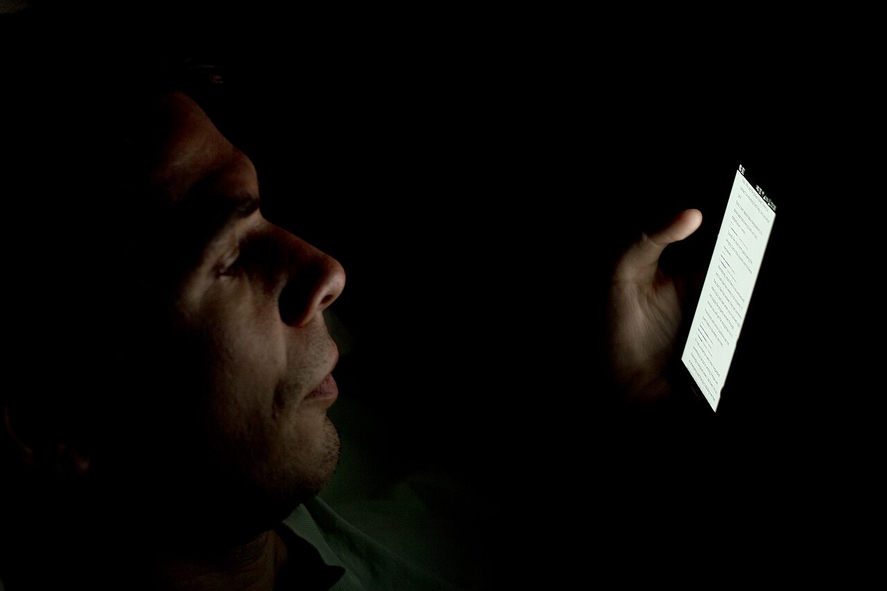 A face lit up by a smartphone screen in the dark